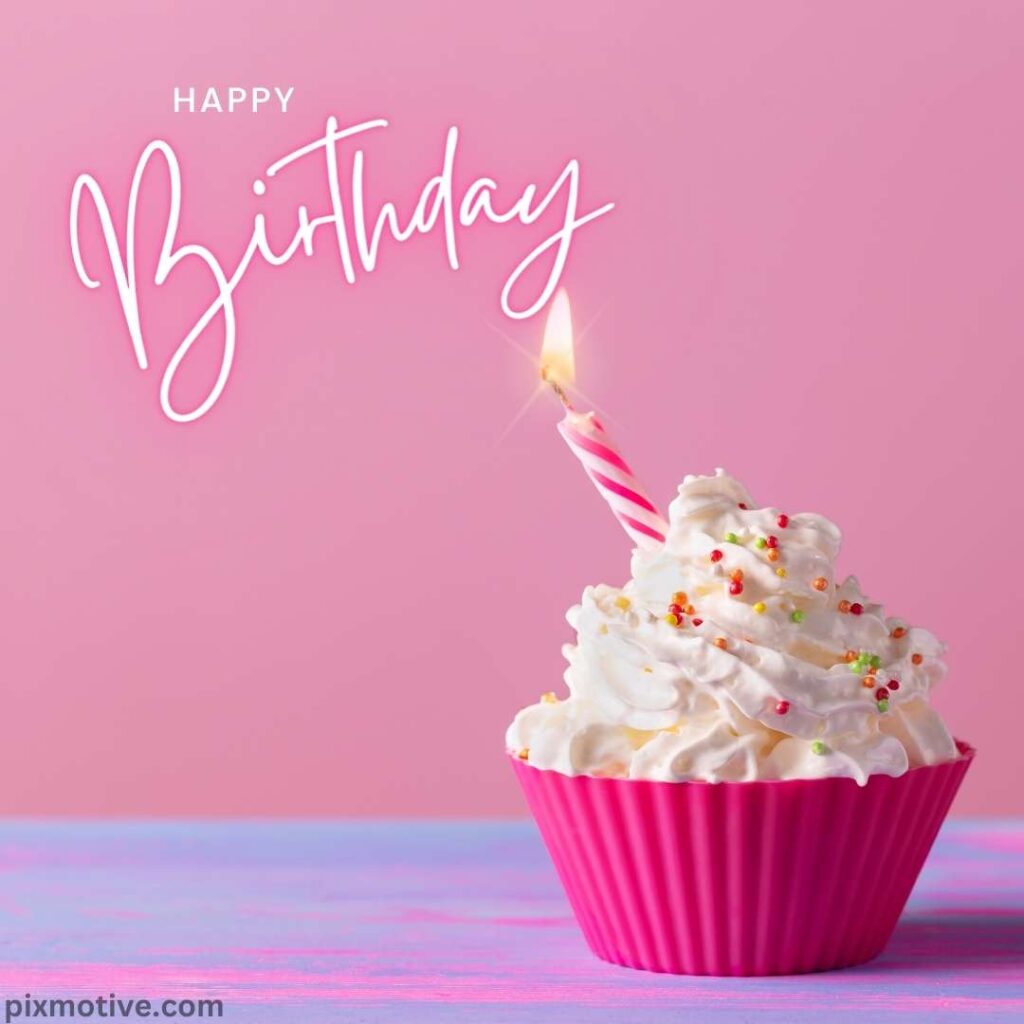Pink cupcake with white frosting topped with colorful sprinkles and a candle birthday decoration